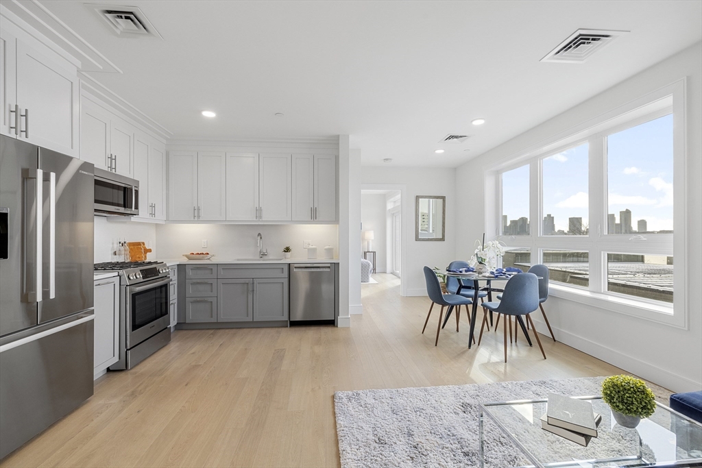 301 Border Street, Unit 611 Boston, MA 02128 - Photo 1 of 32 a kitchen with stainless steel appliances granite countertop a stove a sink a refrigerator a dining table and chairs with wooden floor