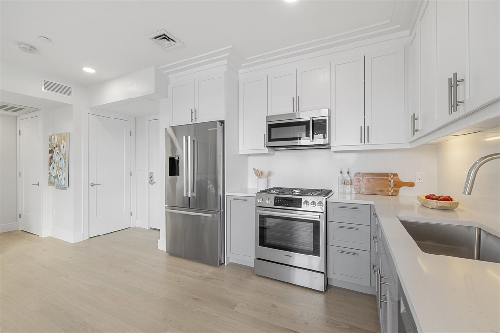 301 Border Street, Unit 611 Boston, MA 02128 - Photo 9 of 32 a kitchen with stainless steel appliances granite countertop a refrigerator stove and sink