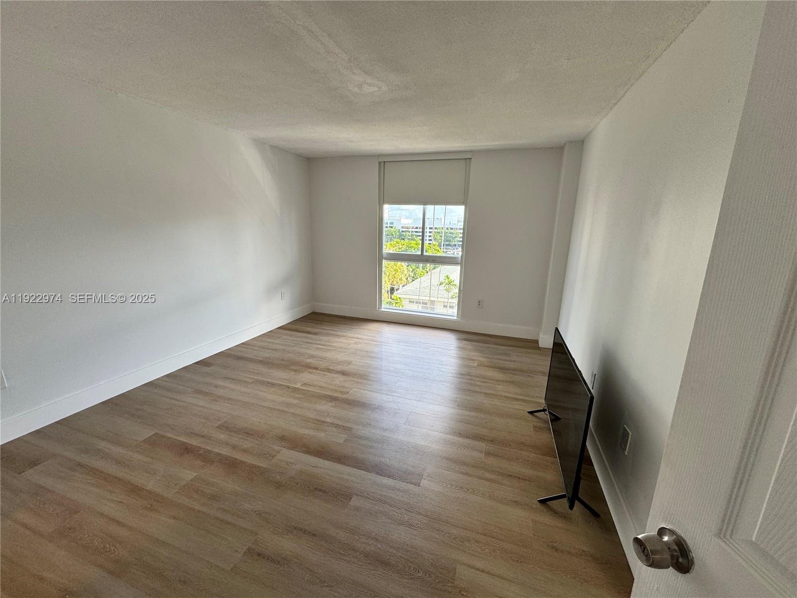 7928 West Drive, Unit 602 North Bay Village, FL 33141 - Photo 10 of 44 an empty room with wooden floor and windows