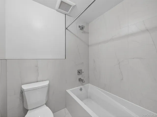 a white toilet sitting next to a bathtub