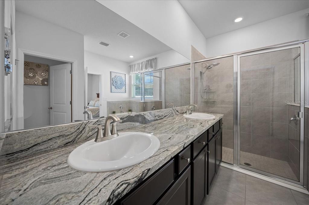 8598 Southwest 59th Terrace Ocala, FL 34476 - Photo 41 of 73 a bathroom with a granite countertop sink a mirror and a shower