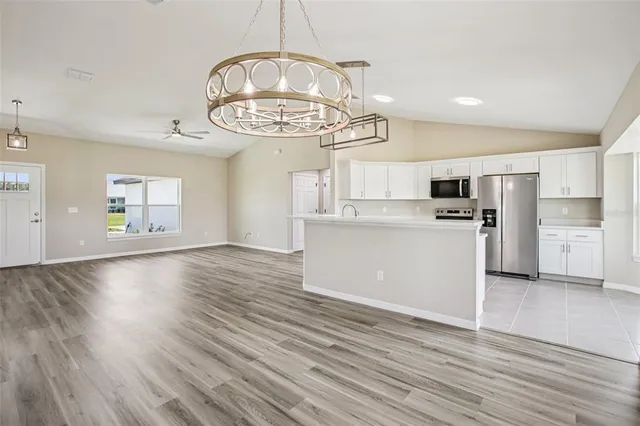 a view of a kitchen with a stove wooden cabinet wooden floor chandelier and a kitchen view