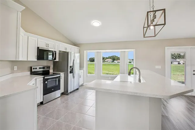 a kitchen with stainless steel appliances a stove a sink a oven a refrigerator cabinets and a window