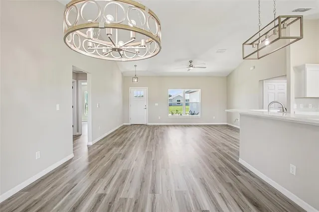 an empty room with wooden floor a chandelier and windows