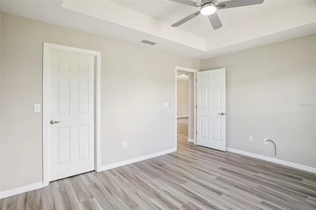 an empty room with a ceiling fan and wooden floor