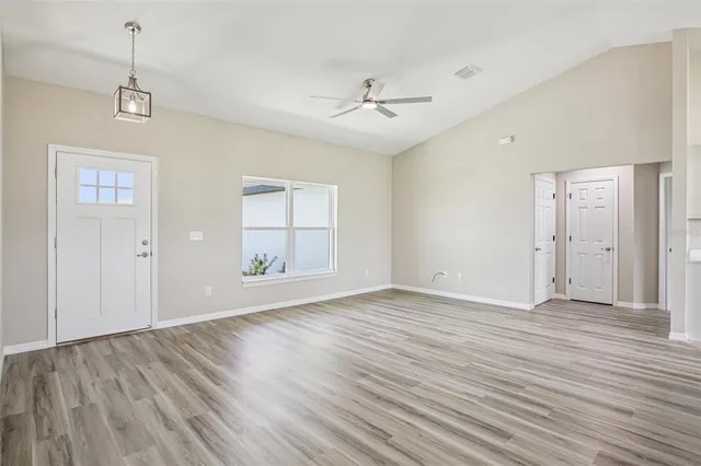 a view of an empty room with wooden floor and a window