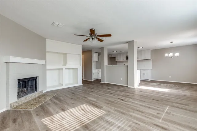 a view of a livingroom with a fireplace a ceiling fan and wooden floor