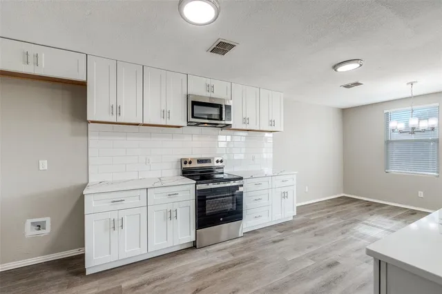 a kitchen with stainless steel appliances white cabinets and a stove top oven