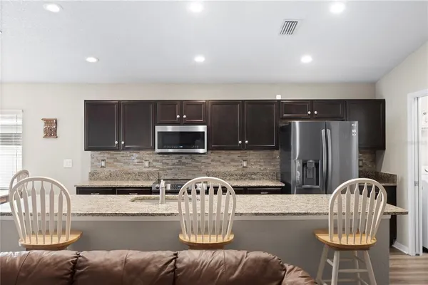 a view of kitchen with stainless steel appliances granite countertop dining table and chairs