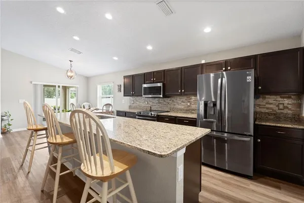 a kitchen with stainless steel appliances granite countertop a table chairs sink refrigerator and microwave