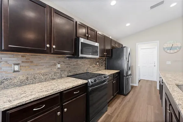 a kitchen with stainless steel appliances granite countertop wooden cabinets and a stove top oven