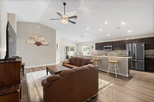 a living room with stainless steel appliances furniture and kitchen view