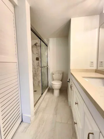 a bathroom with a granite countertop sink toilet and shower
