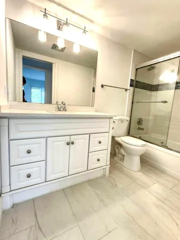a bathroom with a granite countertop toilet sink and mirror