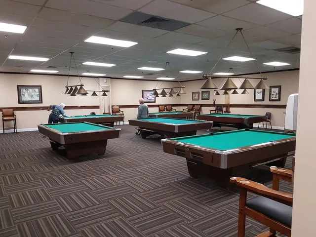 a room with wooden floor pool table and chairs