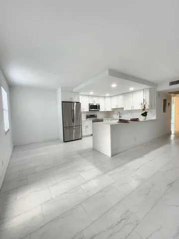a large white kitchen with stainless steel appliances granite countertop a sink and cabinets