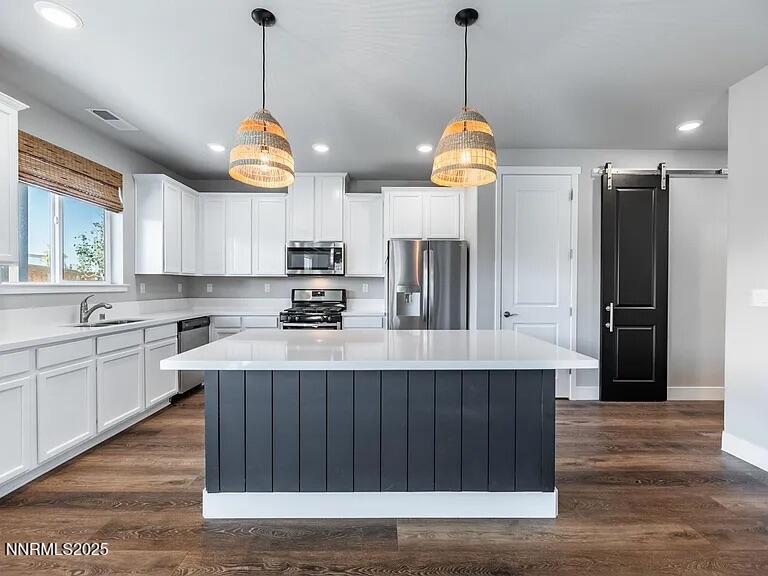 7731 Enclave Key Road Reno, NV 89506 - Photo 7 of 43 a kitchen with stainless steel appliances kitchen island granite countertop a sink a stove and a wooden floors