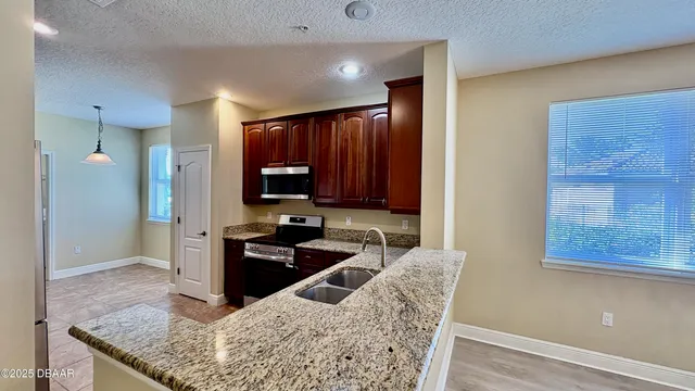 a kitchen with granite countertop wooden cabinets and stainless steel appliances
