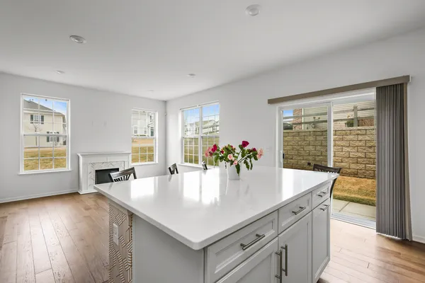 a view of kitchen island with granite countertop a dining table chairs and wooden floor