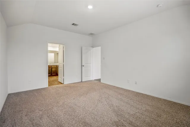 a view of an empty room with closet and bathroom