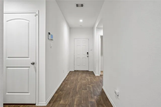 a view of a hallway with wooden floor and a bathroom
