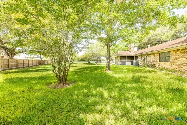 a backyard of a house with large trees and plants