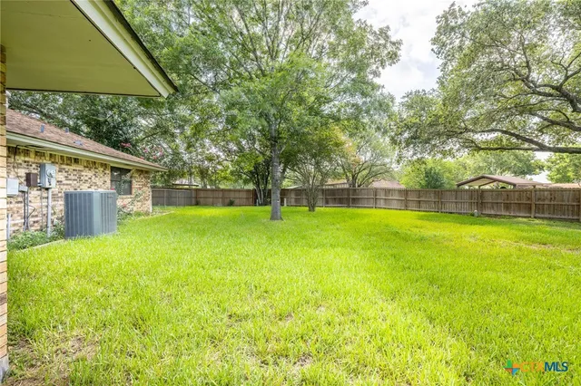 a view of a house with backyard and a tree