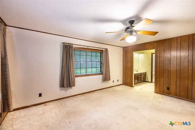 a view of an empty room with chandelier fan and a window