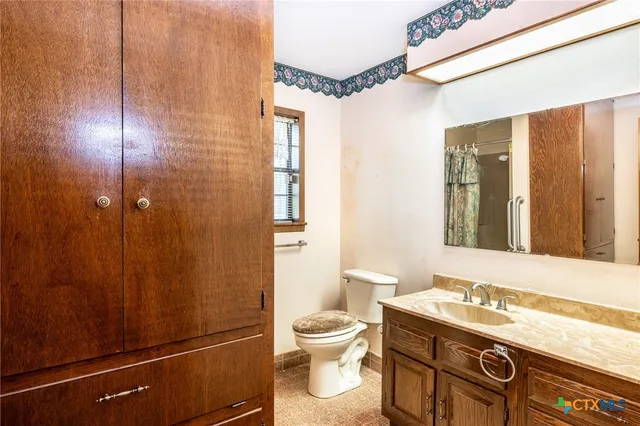 a bathroom with a granite countertop sink toilet a mirror and shower