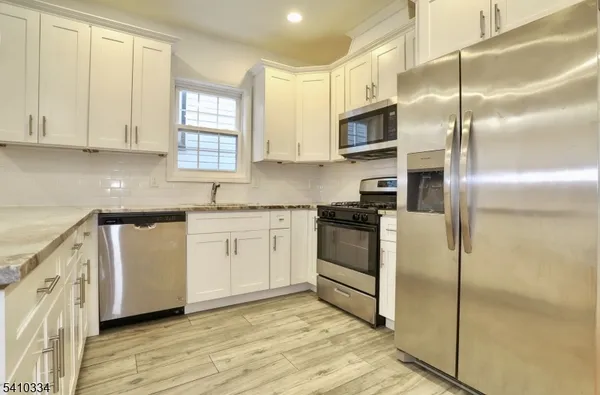 a kitchen with cabinets stainless steel appliances and a window