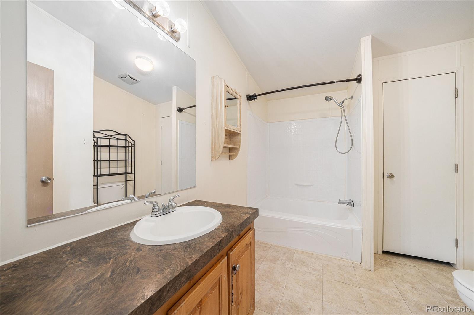 2500 East Harmony Road Fort Collins, CO 80528 - Photo 13 of 23 a bathroom with a granite countertop sink and a mirror a bathtub