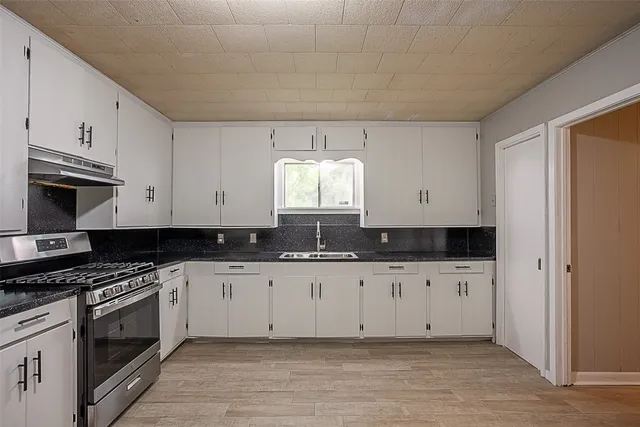 a kitchen with granite countertop a stove and a microwave