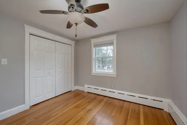an empty room with wooden floor ceiling fan and windows