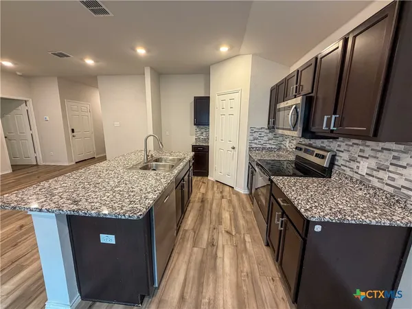a kitchen with stainless steel appliances granite countertop a stove refrigerator and sink