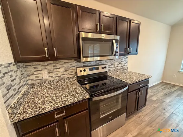 a kitchen with granite countertop wooden cabinets stainless steel appliances and a counter space