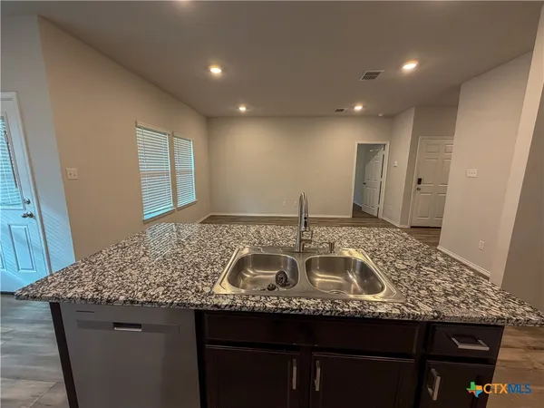 a kitchen with kitchen island granite countertop a sink and a white refrigerator