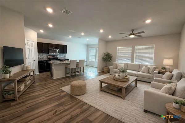 a living room with furniture a flat screen tv and kitchen view