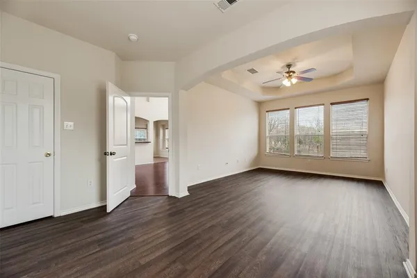 a view of an empty room with a window and wooden floor