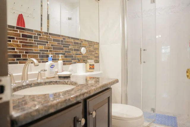 a bathroom with a granite countertop sink a toilet and a mirror