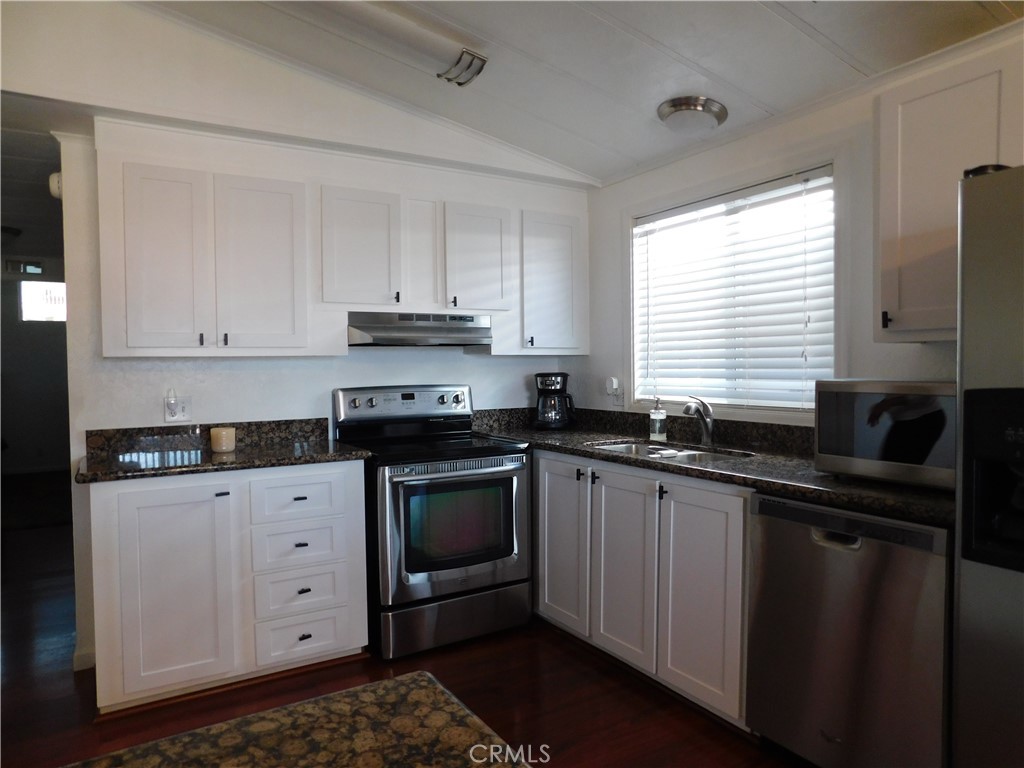 4170 Needles Highway, Unit 55 Needles, CA 92363 - Photo 9 of 39 a kitchen with granite countertop white cabinets sink and stainless steel appliances