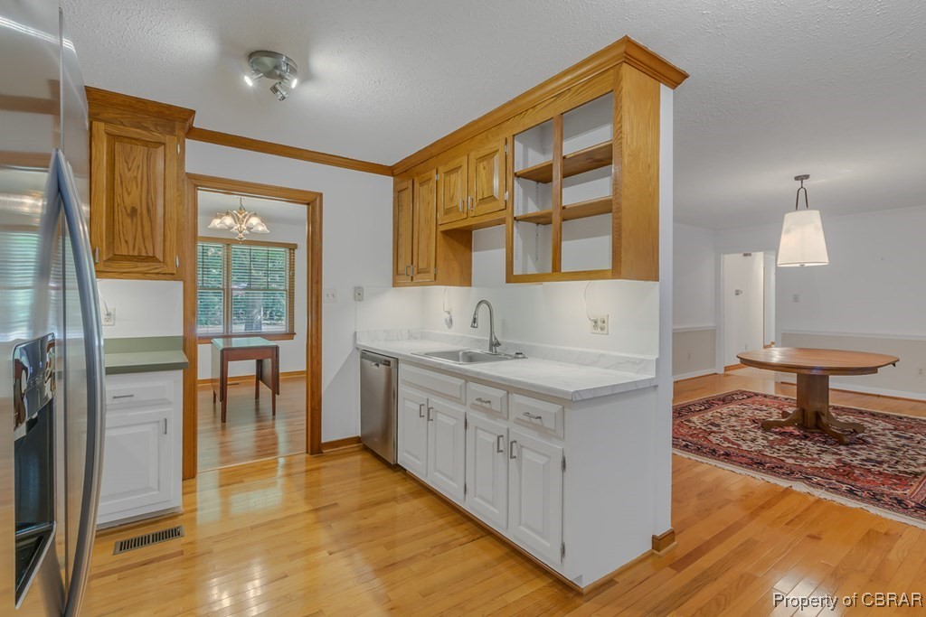 35 Powhatan Road Kilmarnock, VA 22482 - Photo 15 of 42 Kitchen featuring a sink, glass insert cabinets, light wood-type flooring, stainless steel appliances, and visible vents