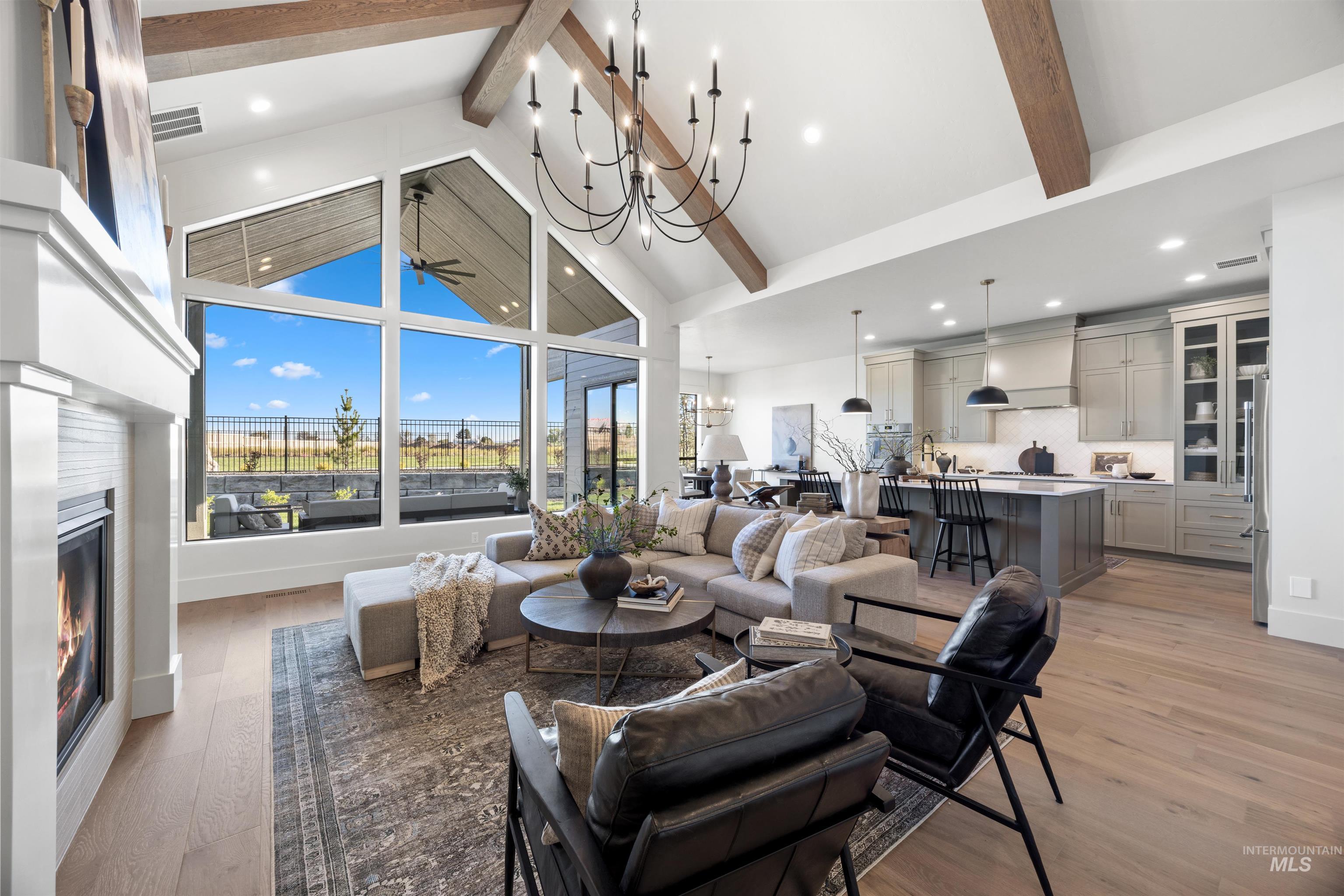 1064 East Snag Street Meridian, ID 83642 - Photo 11 of 44 Living room featuring hanging lights, a glass covered fireplace, light wood-style floors, and ceiling fan