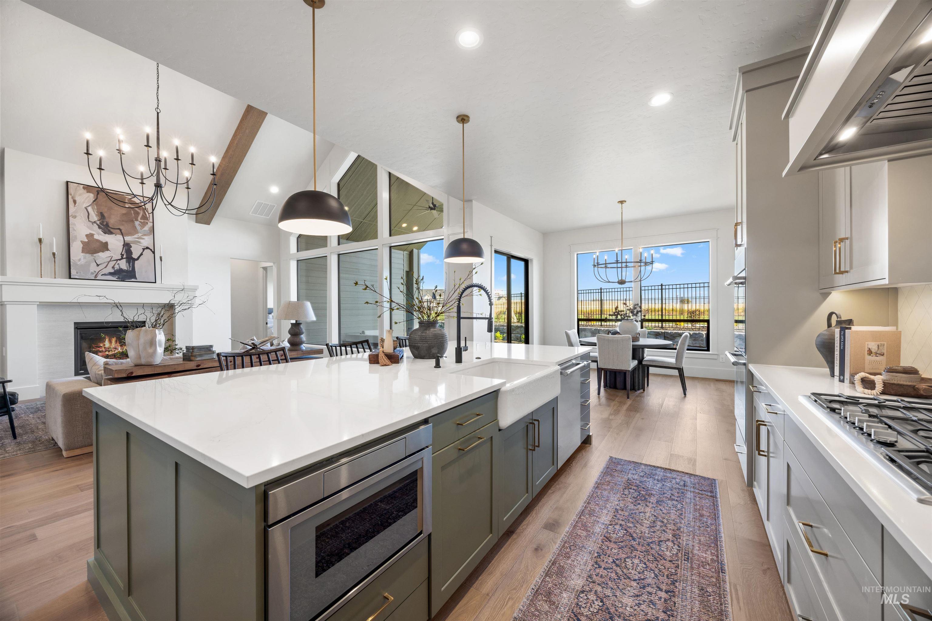 1064 East Snag Street Meridian, ID 83642 - Photo 23 of 44 Kitchen featuring a chandelier, exhaust hood, a high end fireplace, light stone countertops, and vaulted ceiling