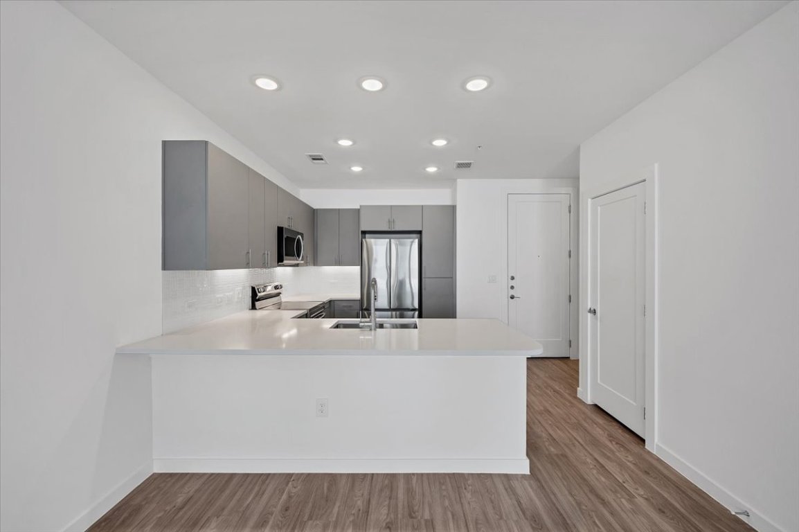 4801 Springdale Road, Unit 1402 Austin, TX 78723 - Photo 10 of 40 a large white kitchen with wooden floors and center island