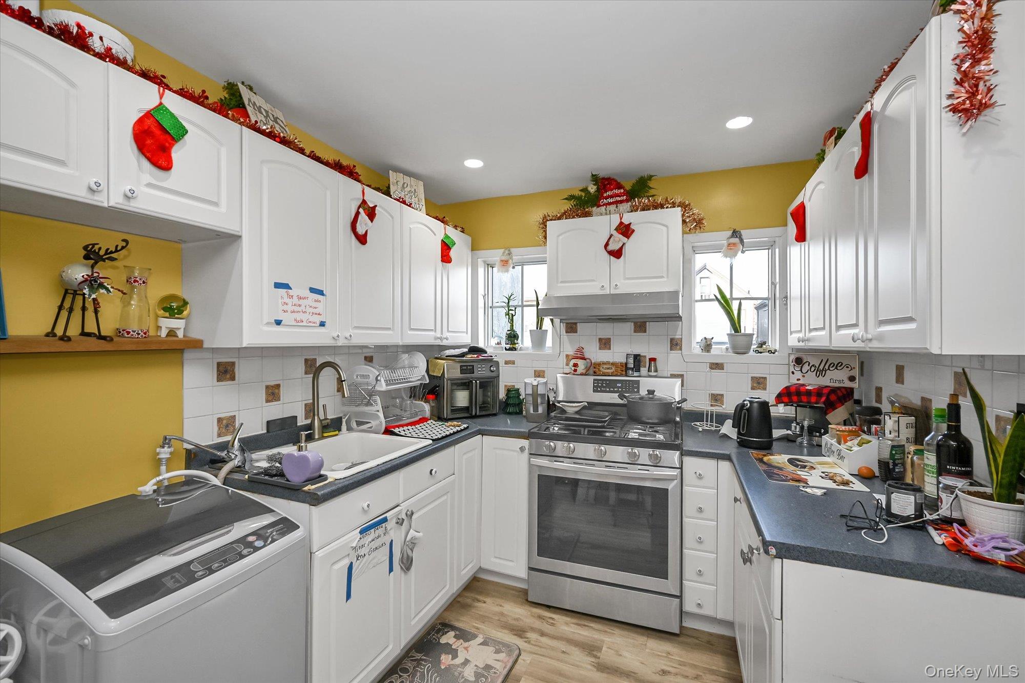 69-25 59th Road Queens, NY 11378 - Photo 14 of 24 Kitchen with washer / dryer, gas range, dark countertops, white cabinets, and recessed lighting