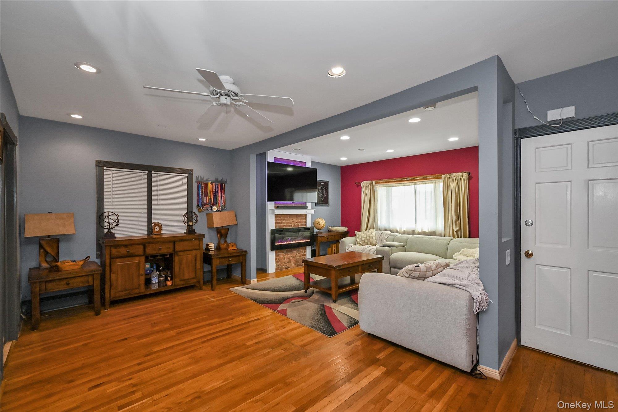 69-25 59th Road Queens, NY 11378 - Photo 4 of 24 Living room featuring a ceiling fan, recessed lighting, wood finished floors, and a glass covered fireplace