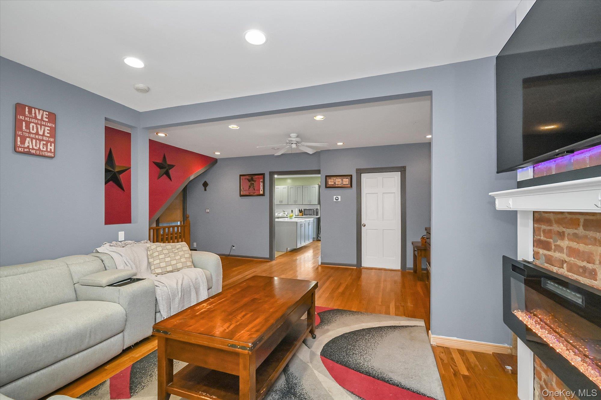 69-25 59th Road Queens, NY 11378 - Photo 6 of 24 Living area featuring recessed lighting, wood finished floors, a ceiling fan, and a glass covered fireplace
