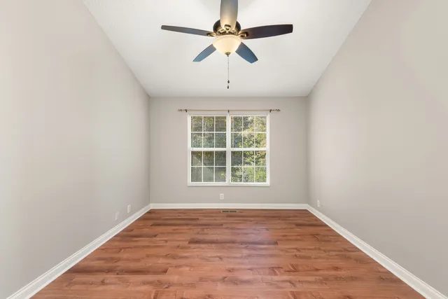 an empty room with a window and a fan