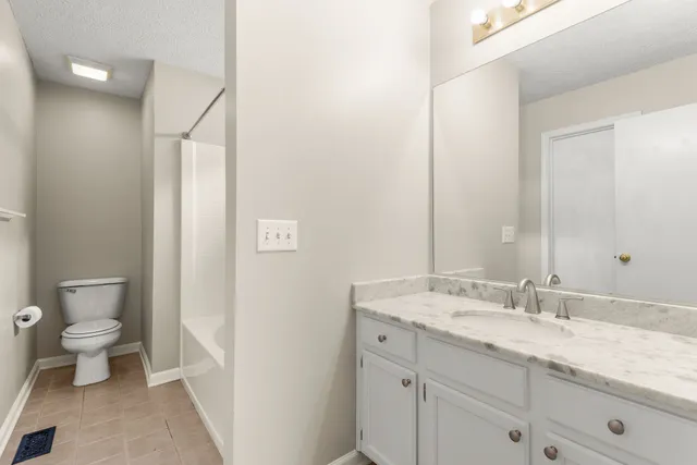 a bathroom with a granite countertop sink a toilet and a mirror