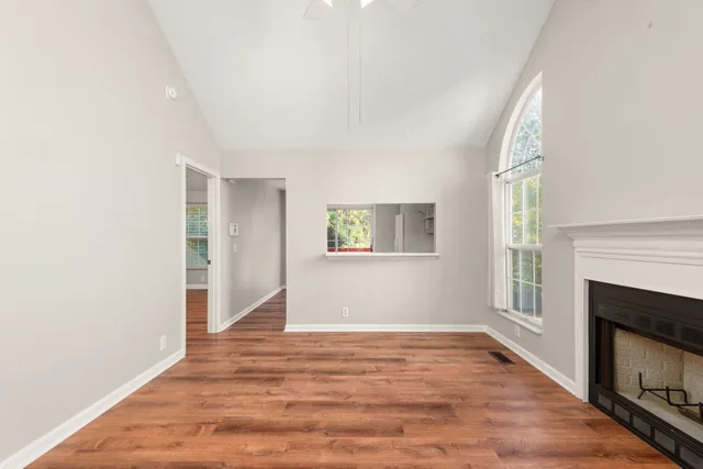 a view of an empty room with wooden floor and a window